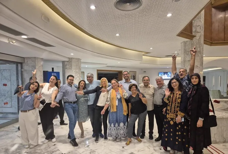 Les membres de l'ATCCR posent ensemble, joyeux, dans le hall d'un hôtel.
