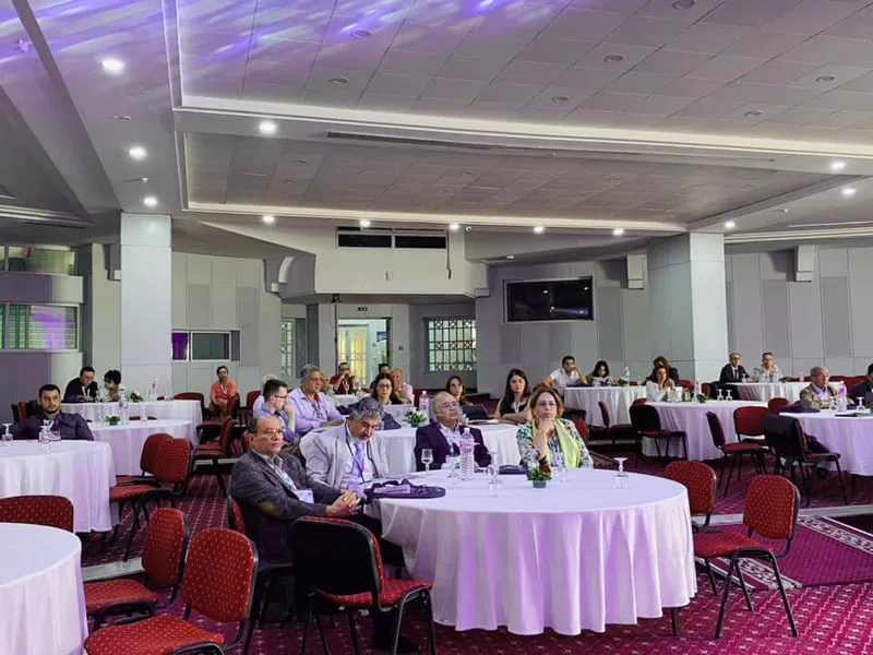 Salle plénière avec des congressistes assis à des tables rondes.